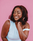 Woman with a short hairstyle smiling against a pink background