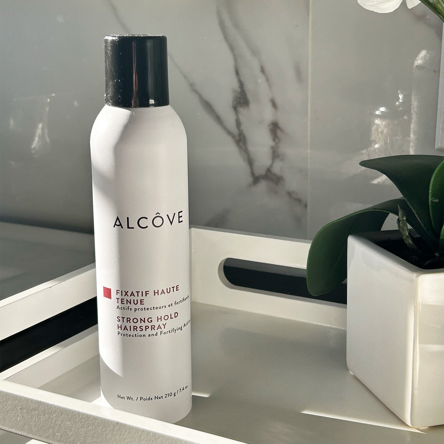Bottle of Alcove Hair Strong Hold Hairspray in a bathroom